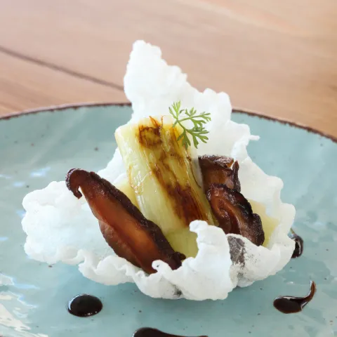 Calçots confitados con shiitake asado y salsa adobo sobre papel de arroz frito