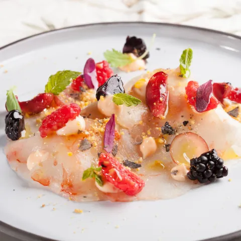 Carpaccio de gamba con mayonesa elaborada con su coral y fruta de temporada.