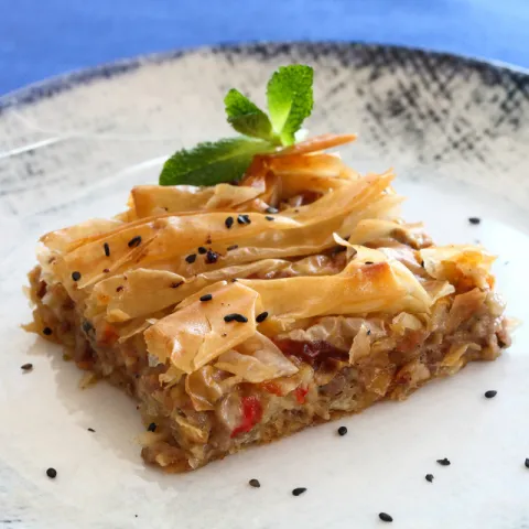Pastel griego a nuestro estilo con carne picada de ternera jugosa, verduras, hierbas mediterráneas y queso fundido en masa filo crujiente