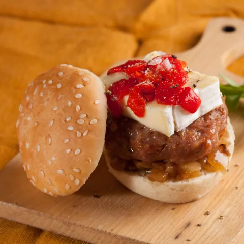 Mini hamburguesa de xai amb pa de sèsam, ceba caramel·litzada, formatge brie i pebrot del piquillo.