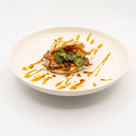 Secreto de cerdo con adobo oriental, hierbas frescas, encurtidos caseros y mayosriracha.