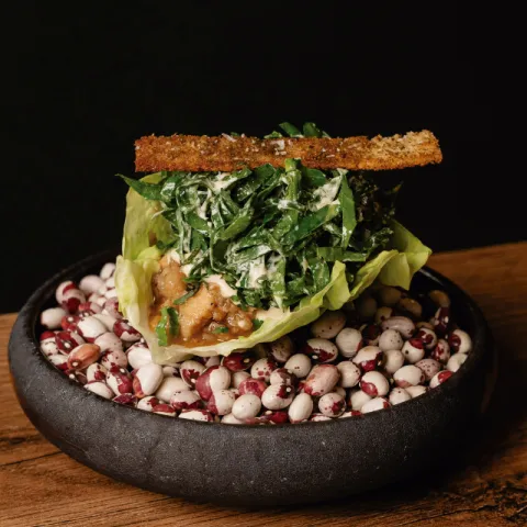 Sobre una hoja de lechuga, cerdo negro mallorquín cocinado lentamente, ligado con su jugo y con hierbas frescas