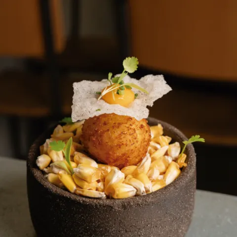 Croqueta cremosa de ají de gallina, con emulsión de ají amarillo, maíz crujiente y encurtidos