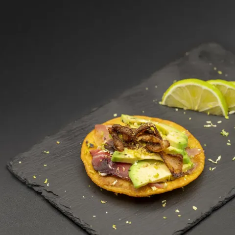 Garnacha frita con atún, aguacate, cebolla frita y ralladura de lima