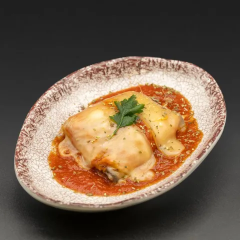 Rollito de berenjena relleno de york, queso y salsa de tomate, cubierto con queso fundido