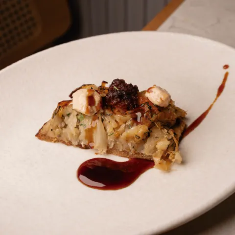 Coca, cebolla caramelizada, foie y reducción de Manto Negro