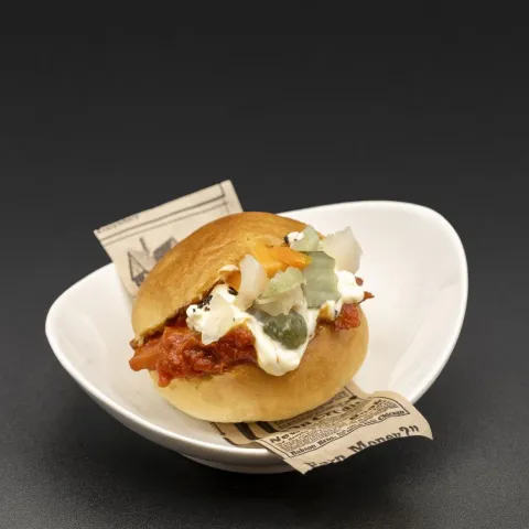 Mini brioche relleno de ragú de calamar picante estilo diabla, mayonesa de limón ahumado y encurtidos