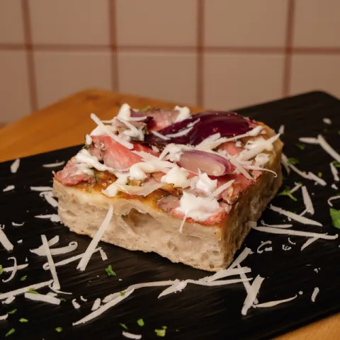 Pizza de base blanca con mozzarella, solomillo de ternera marinado con chimichurri, alioli de patata y cebolla