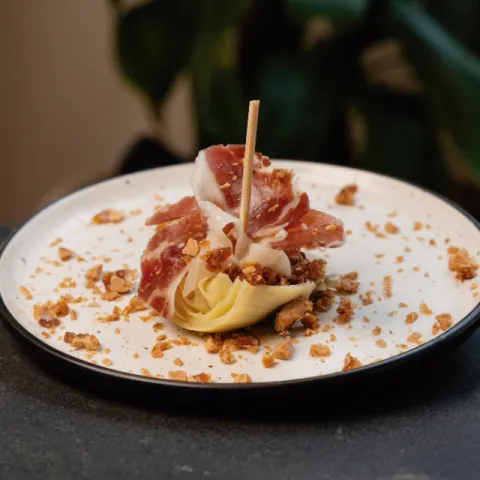 Montadito de jamón ibérico sobre corazón de alcachofa y cubierto de praliné de almendras mallorquinas