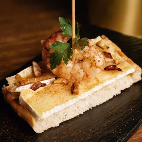 Tosta de pan de cristal con gambas de Soller al ajillo, queso brie fundido y reducción de miel y brandy dulce y picante: la combinación perfecta